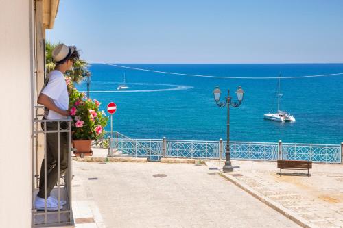 a woman standing on a pier looking at the ocean at Hotel Al Madarig in Castellammare del Golfo