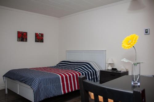 a bedroom with a bed and a table and a vase with a sunflower at Motel de la mer in Rimouski