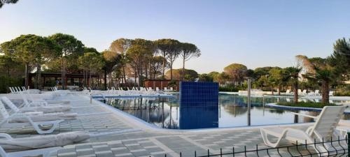 una piscina con sillas blancas, agua y árboles en Villa Shera en Mullini i Danit