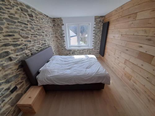 een slaapkamer met een bed en een bakstenen muur bij Maison de vacances familiale à Vresse s/ Semois in Vresse-sur-Semois