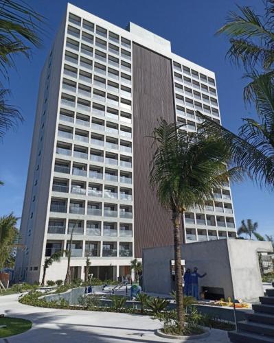 a tall building with a palm tree in front of it at Salinas Premium Resort in Salinópolis