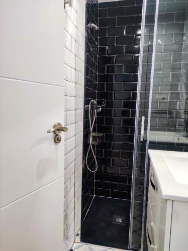 a bathroom with a shower with a black tile wall at Casa Liberatina in Cudillero