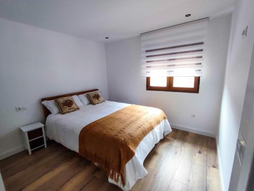 a white bedroom with a bed and a window at Casa Liberatina in Cudillero