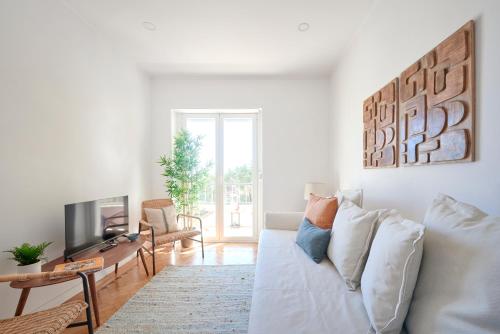a living room with a white couch and a tv at Enjoy the Sunny Balcony, By TimeCooler in Lisbon