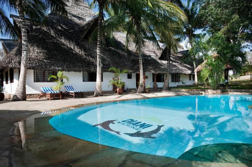 a swimming pool in front of a resort with a dolphin painted on it at Diani Marine Divers Village in Diani Beach