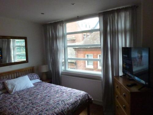 a bedroom with a bed and a television and a window at Lovely 2 bed flat in the VERY CENTRE of Newcastle in Newcastle upon Tyne