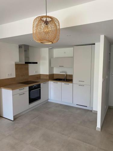 une cuisine avec des armoires blanches et un lustre dans l'établissement T2 GARDEN BEACH, à Saint-Cyr-sur-Mer