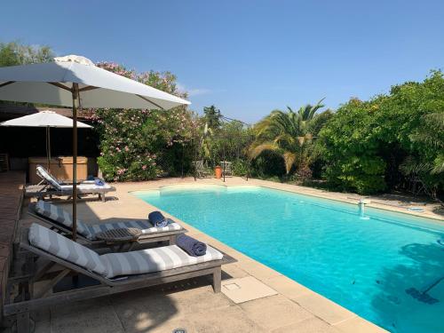 a swimming pool with two lounge chairs and an umbrella at Villa La Rose des Vents in Tourrettes
