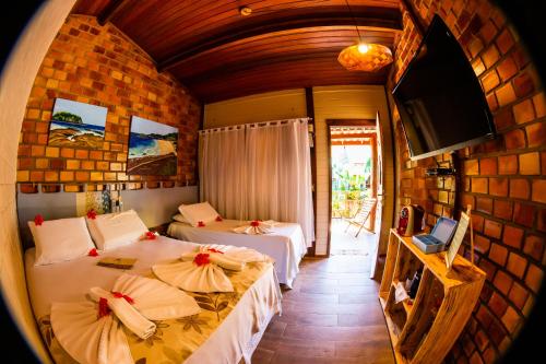 a room with two beds and a television in a room at Pousada Mar Aberto in Fernando de Noronha