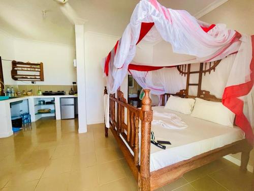 una camera con letto in legno a baldacchino di Kome beach Apartment one a Jambiani