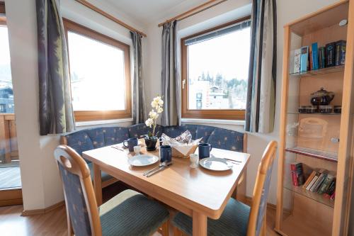 a dining room table with two chairs and two windows at Alpin Apartments in Maria Alm am Steinernen Meer