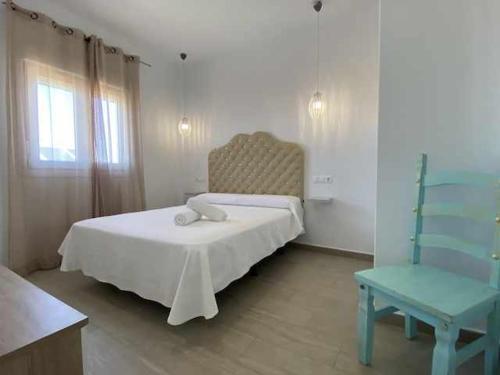 sypialnia z białym łóżkiem i niebieskim krzesłem w obiekcie Apartamento 4 Atlantico w Kadyksie