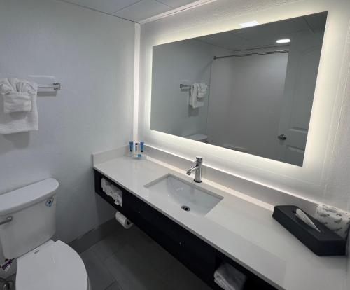 a bathroom with a toilet and a sink with a mirror at Tropical Seas Hotel in Myrtle Beach