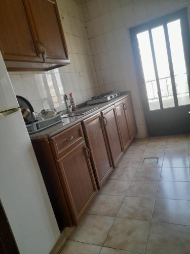 a small kitchen with wooden cabinets and a window at Al Karawan Hotel Apartments in Amman