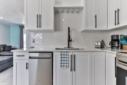 a white kitchen with white cabinets and a sink at Coastal Waters in New Smyrna Beach