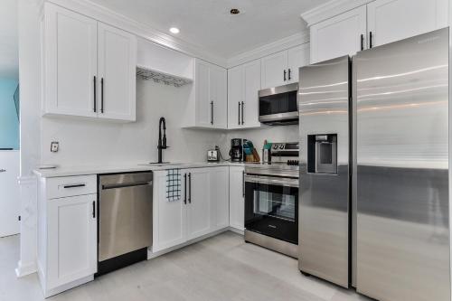 a kitchen with white cabinets and stainless steel appliances at Coastal Waters in New Smyrna Beach