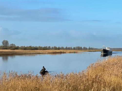 a man is standing in the middle of a lake at Ollediek in Houwerzijl