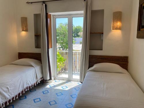 two beds in a room with a view of a balcony at Hotel La Piazzetta in Mérida