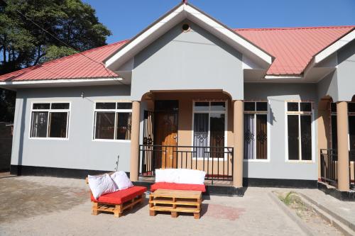 una casa con 2 sillas y techo rojo en PEARL LULU MODERN BNB Homestay, en Dar es Salaam