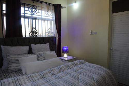 a bedroom with a bed with a purple lamp on a table at PEARL LULU MODERN BNB Homestay in Dar es Salaam