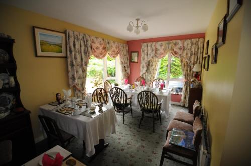 a dining room with a table and chairs and windows at Haywoods B&B in Donegal