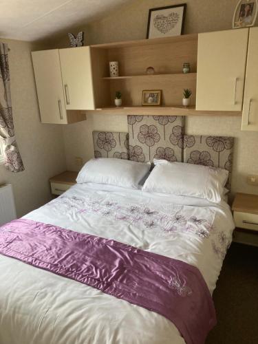 a bed with a purple and white blanket on it at Luxury caravan at Turnberry - short walk to beach in Girvan