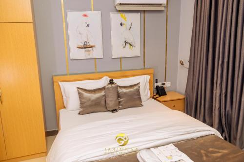 a bedroom with a white bed with pictures on the wall at Golden Six Hotel and Restaurant in Lekki