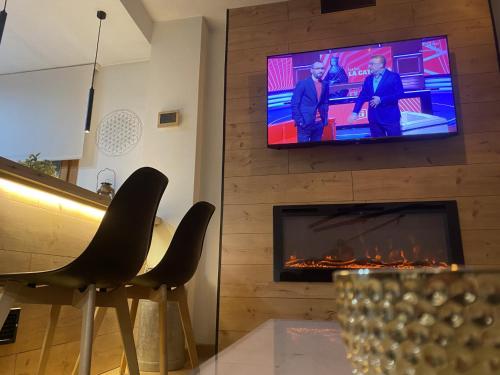 a living room with a fireplace and a tv on a wall at CAL DOMÈNEC RIALP - Dúplex con encanto - Se admiten mascotas in Rialp