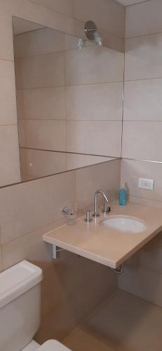 a bathroom with a sink and a toilet and a mirror at Departamento Solares - San Martin in Bahía Blanca