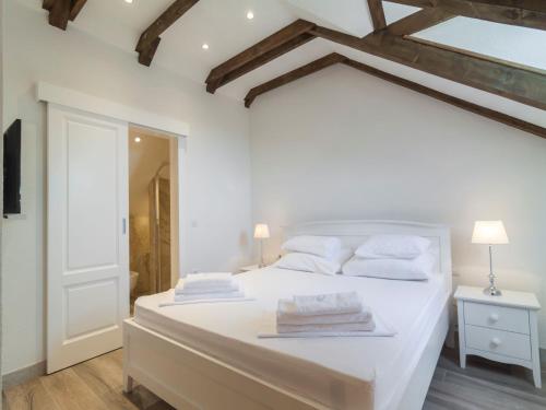 a white bedroom with a large bed with white pillows at Villa Joe in Čilipi