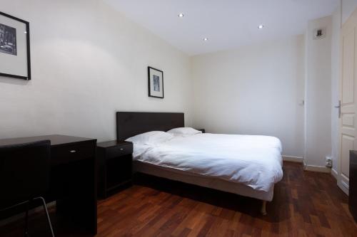 a bedroom with a white bed and a wooden floor at Hotel Mimosa Paris in Paris