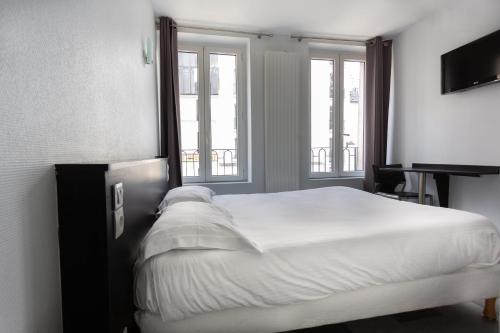 a bedroom with a large white bed and two windows at Hotel Mimosa Paris in Paris