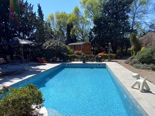 une piscine avec de l'eau bleue dans une cour dans l'établissement La roulotte à Juju, à Le Bosc