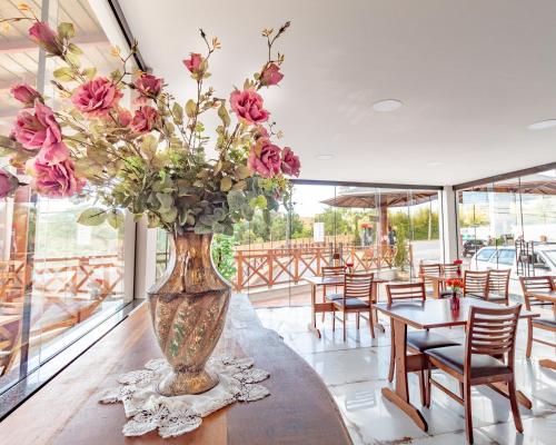 a vase with flowers on a table in a restaurant at Pousada Posto Monte Verde in Monte Verde