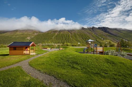 un parque con parque infantil y una casa pequeña en Hótel Tjarnir, en Ljósavatn