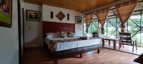 a bedroom with a bed in a room with windows at Eco Hotel Aldea -AMAZONAS in Puerto Nariño