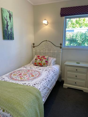 a small bedroom with a bed and a window at Cottage on Kent in Arrowtown