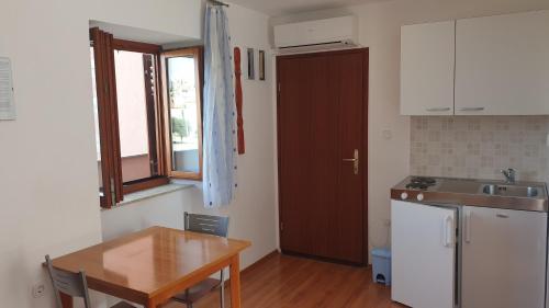 La cuisine est équipée d'une table, d'un évier et d'un réfrigérateur. dans l'établissement Apartments Rosa, à Mali Lošinj