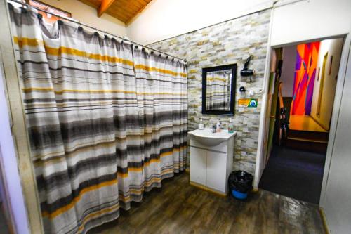 baño con lavabo y cortina de ducha en Gecko Hostel, en Pucón