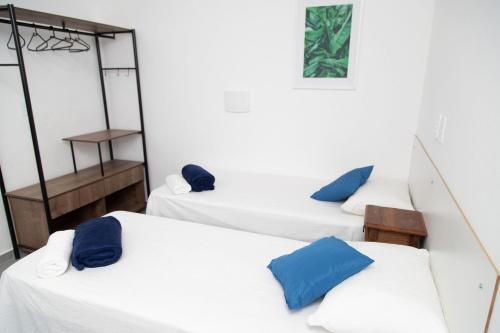 three beds in a room with blue pillows on them at Studio USP by OBA in São Paulo