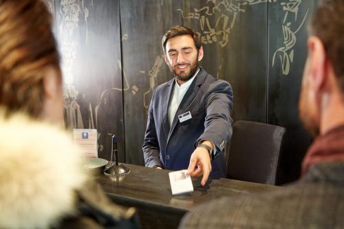 Un uomo in giacca e cravatta seduto a un tavolo di Pure Montagne Resort & Spa a Saint-Martin-Vésubie