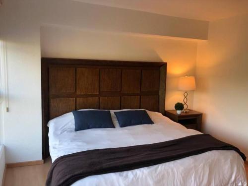 a bedroom with a large bed with a wooden headboard at Hermoso Depto de 3 rec ubicado corazón de Santa Fe in Mexico City