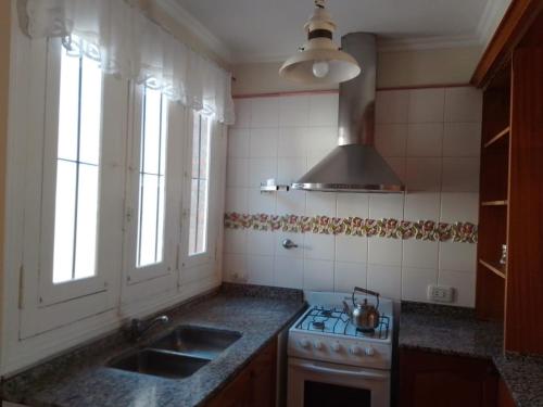 eine Küche mit einer Spüle, einem Herd und Fenstern in der Unterkunft Casa al rio in San Pedro