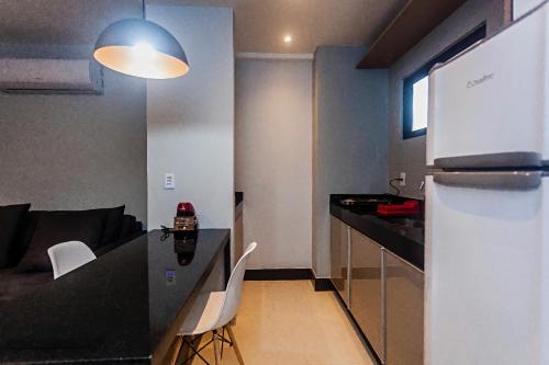 a small kitchen with a black counter top and a refrigerator at Flat em Lagoa Nova, Mobiliado e Aconchegante in Natal