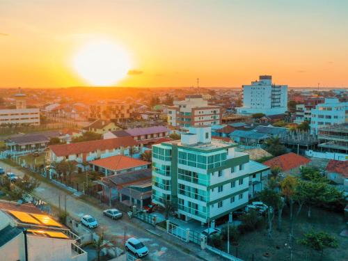 a city skyline with the sunset in the background at Tropical Tramandaí in Tramandaí