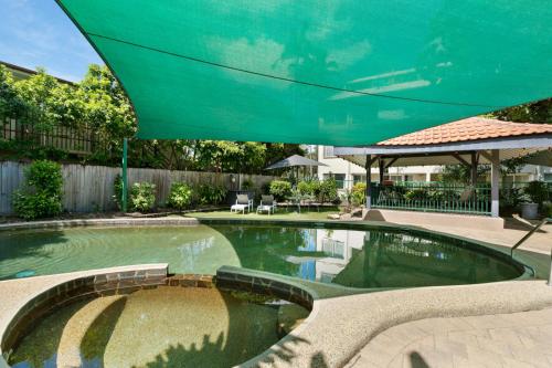 a pool with a large umbrella in the middle of it at Reef Gateway Apartments in Cairns