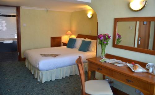 a hotel room with a bed and a desk and a mirror at The Ayrshire and Galloway in Ayr