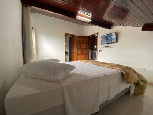 a white bed in a room with a window at Souza Reis Apart - Unidade 2 in São Thomé das Letras