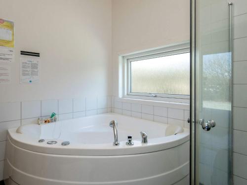 La salle de bains est pourvue d'une baignoire blanche et d'une fenêtre. dans l'établissement Holiday home Vestervig XXXII, à Vestervig
