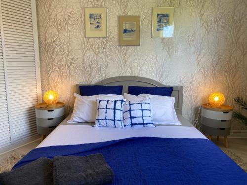 - un lit avec des oreillers bleus et blancs et 2 lampes dans l'établissement Jarry Entre Chien et Loup, à Baie-Mahault